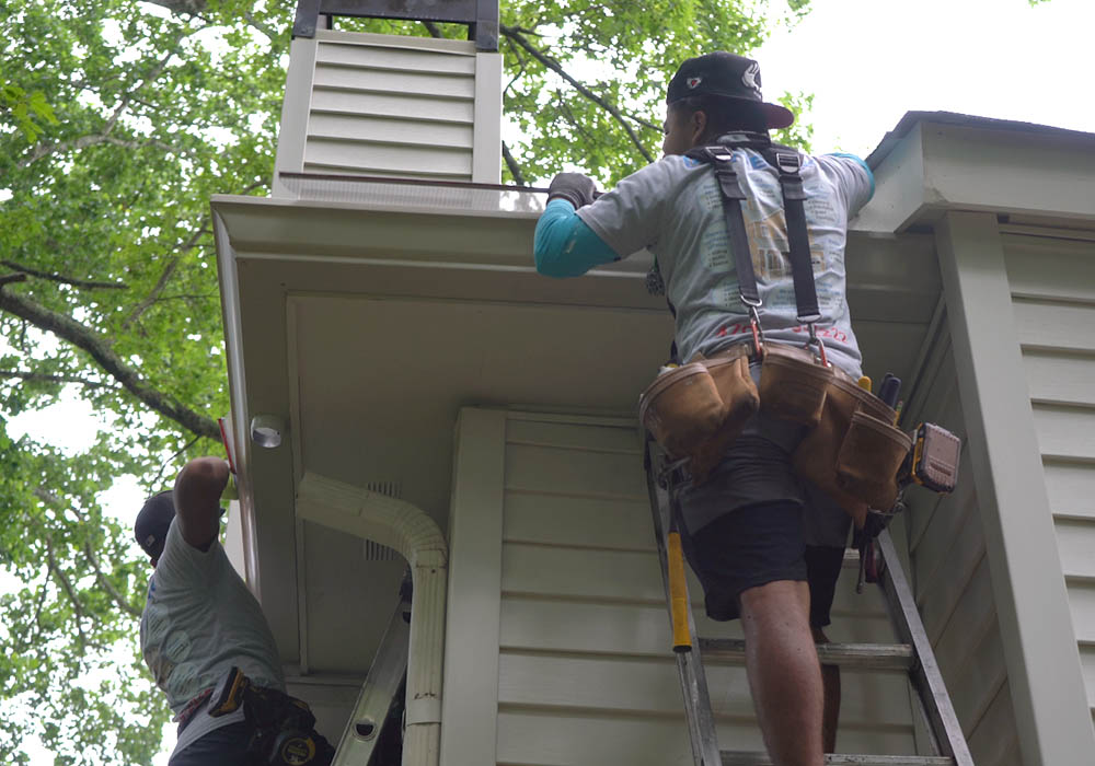 Technician installing leaf guard system on home gutter