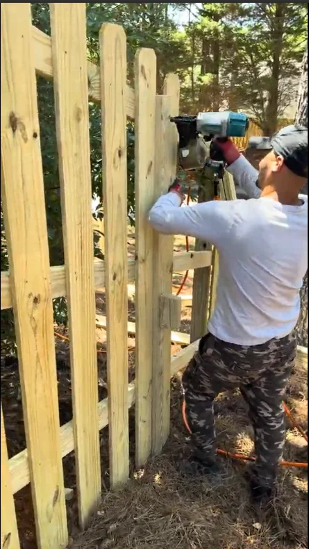 Gutter Bro technician installing fence with a nail gun