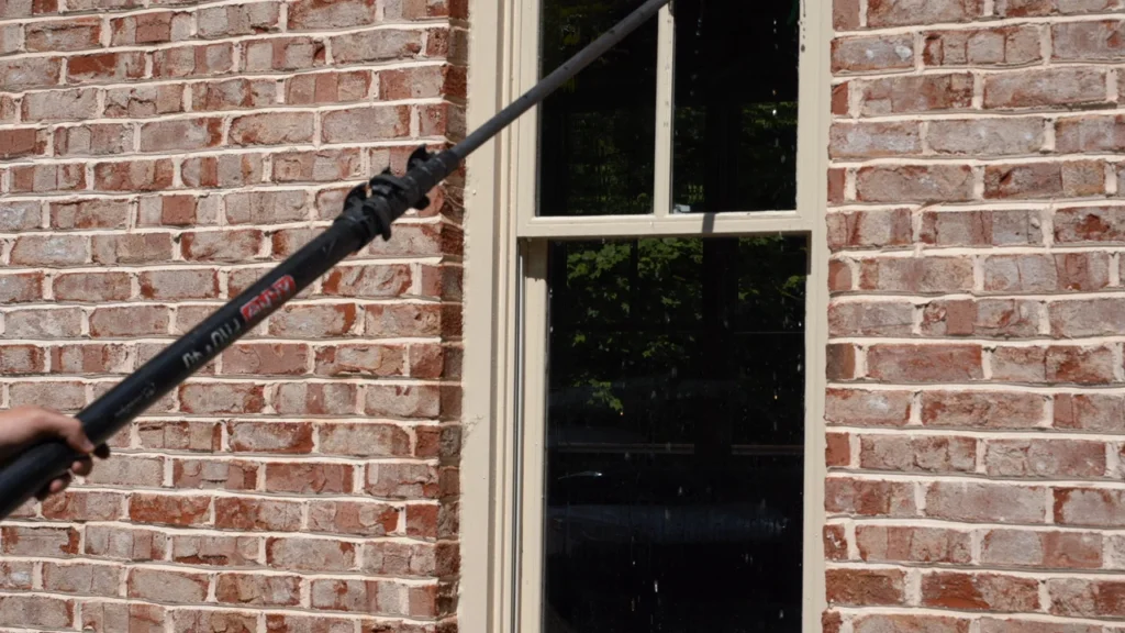 Gutter Bro technician scrubbing and washing a large window with a cleaning brush